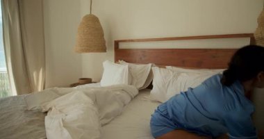 Mavi üniformalı bir kadın yatak odasından, evden okyanus manzarasına bakıyor. Rahatlama, tefekkür, sükunet, yalnızlık, seyahat, yaşam tarzı.