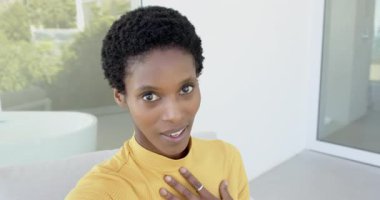 Kamera, balıkçı yaka kazaklı Afro-Amerikalı bir kadını teras vlogunda konuşurken çekiyor. Portre, yaşam tarzı, modern, iletişim, açık hava, canlı, anlamlı