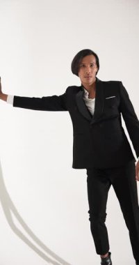 Dikey video: Siyah takım elbiseli şık adam modern moda stüdyosunda güven içinde poz veriyor. stil, erkek giyim, zarafet, özgüven, giysi, fotoğraf çekimi.