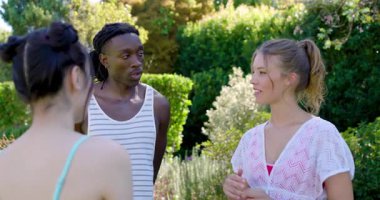 Çeşitli arkadaşlar sarılmadan ve bahçede portre için poz vermeden önce kahkahalar atıp selamlaşıyorlar. Açık hava, yoldaşlık, neşe, gündelik, canlı, bağlantı, boş zaman