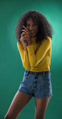 Dikey video: Sarı bluzlu ve kot şortlu neşeli kadın ellerini çırpıyor, heyecanlanıyor. Neşeli, mutluluk, alkış, kutlama, gündelik, yaz