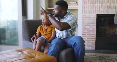 Koltuktan işaret eden, Afrikalı Amerikalı baba ve oğul evde kaynaşmak için gıdıklanıyor ve sarılıyorlar. Aile, bağ, sıcaklık, şefkat, neşe, rahatlık, birliktelik