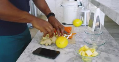 Modern mutfakta blender ile havuç ve zencefil doğrayan Afro-Amerikalı bir adam. Yemek, sebze, mutfak, hazırlık, sağlıklı, modern, malzemeler