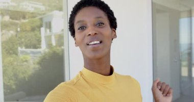 Kamera Afrika kökenli Amerikalı bir kadın balkondaki sürgülü kapıda dikilip konuşuyor, işaret ediyor. Kendinden emin, anlamlı, iletişim, yaşam tarzı, modern, açık hava, pozitiflik.