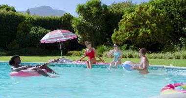 Beyaz adam içkisini bitirdikten sonra çeşitli arkadaşlar havuzda plaj topu oynayıp duruyor. Eğlence, eğlence, yaz, arkadaşlık, oyun, rahatlama, açık hava.