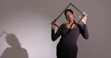 Stüdyoda, Hint kadın model siyah metal çerçeve etrafında dönüyor dramatik gölgeler yaratıyor. Çağdaş, minimalist, sanatsal, moda, siluet, monokrom, yaratıcı