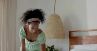 Genç bir kadın yatakta uzanıyor, evdeki akıllı telefondan sevinçle mesaj atıyor. İletişim, teknoloji, yaşam tarzı, mutluluk, rahatlamış, dijital