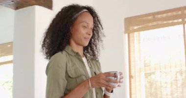 Kadın evde kahveden zevk alıyor, gülümsüyor ve rahatlamış görünüyor. Yaşam tarzı, rahatlama, evcil, rahat, sabah, boş zaman