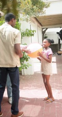 Dikey video: Aile tatilde eğleniyor, gülümsüyor ve büyüleyici villa girişinin dışında konuşuyor. Aile gezisi, mutluluk, açık hava, kaynaşma, seyahat, boş zaman