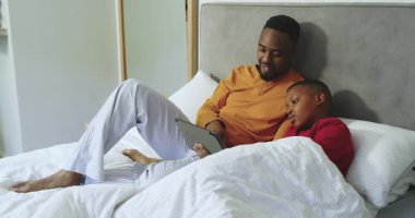 Afro-Amerikalı baba ve oğul yatakta tıkırdıyor ve kaydırıyor, öğrenme içeriğini paylaşıyorlar. Aile, okur yazarlık, bağlanma, eğitim, teknoloji, konfor, sıcaklık