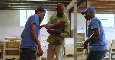 Afro-Amerikan mürettebatı, denetçi tableti işaret ettikten sonra alışveriş istasyonlarına gidiyor. İnşaat, takım çalışması, dijital planlama, güvenlik donanımı, marangozluk, sanayi, işbirliği