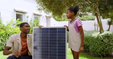 Bahçeye güneş paneli kuruluyor, Afrikalı Amerikalı baba ve çocuk yenilenebilir enerjiyi öğreniyor. sürdürülebilirlik, çeşitli aile, eğitim, bağlanma, takım çalışması, kurulum