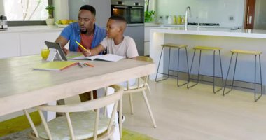 Afro-Amerikalı babaya meyve suyu getirmek oğlunu tablet ödevlerine yönlendirmek. Aile, akıl hocalığı, eğitim, bağlanma, samimiyet, canlılık, modern