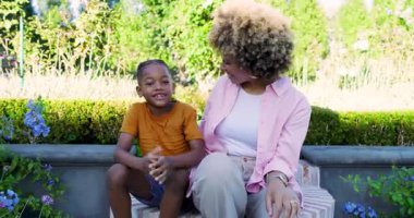 Afrikalı Amerikalı anne ve oğul bahçedeki tuğla bankta birbirine sarılıyorlar. Aile, bağ, doğa, açık hava, sevgi, mutluluk, boş zaman