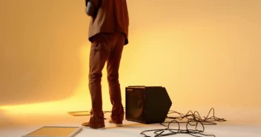 Orta yaşlı Afrikalı Amerikalı adam hoparlöre doğru yürüyor sonra stüdyoda oturuyor ve güneş gözlüğü takıyor. Müzik, dinleme, performans, eğlence, modern, dinamik, gündelik