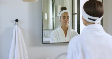 Yansımaya bakan, ped karıştıran banyo lavabosunu temizlemek için yüzünü silen, fotokopi çeken bir kadın. Cilt bakımı, güzellik, kişisel bakım, hijyen, sağlık, minimalizm, rahatlama.