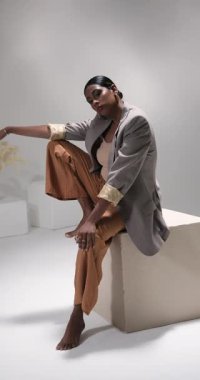 Dikey video: Modern moda stüdyosunda zarif pozlar veren şık giyimli kendine güvenen kadın. stil, zarafet, güven, modellik, fotoğrafçılık, giyim