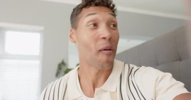 Akıllı telefonu destekleyen, çizgili polo giyen orta yaşlı bir adam yatak odasında gri yatak başlığıyla mesaj kaydediyor. Günlük, günlük, yaşam tarzı, iç mekan, ev, iletişim, anlamlı