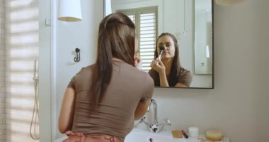 Banyo aynasından pofuduk fırça alan, pudra karıştıran, sonra da ukalalık taslayan bir kadın. Güzellik, bakım, zarafet, kişisel bakım, cilt bakımı, yaşam tarzı, doğal ışık.