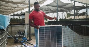 Kırmızı gömlekli adam seraya güneş paneli kuruyor, yenilenebilir enerjiye odaklanıyor. kurulum, güneş enerjisi, teknoloji, sürdürülebilirlik, elektrikçi, yenilik