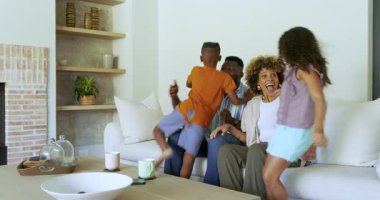 Çeşitli aileler, oturma odasındaki kanepede çocuklara sarılıp onları gıdıklıyor. Aile, birliktelik, sıcaklık, evcil, yaşam tarzı, samimi, çok kültürlü.