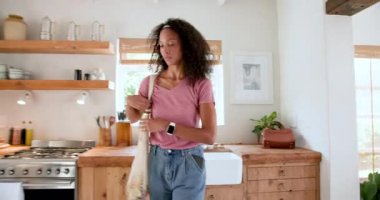 Tekrar kullanılabilir poşetlerden paketleri açmak, mutfakta gülümseyen bir kadın, evde. Sürdürülebilirlik, çevre dostu, alışveriş, mutluluk, yaşam tarzı