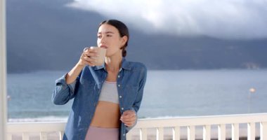 Kadın sabah kahvesini balkonda içiyor. Huzurlu okyanus manzarası, fotokopi odası. Rahatlama, huzur, yaşam tarzı, rahatlık, deniz.