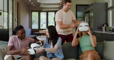 Çeşitli arkadaşlar tableti tıklatırken ve demo denemesi yaparken evde beyaz VR kulaklıkları veriyor ve ayarlıyorlar. Teknoloji, sosyalleşme, eğlence, yaşam tarzı, modern, işbirlikçi, canlı