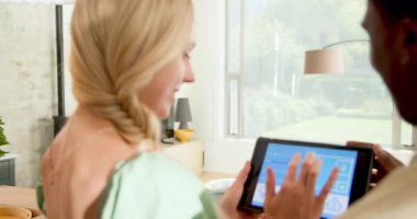 Modern ada tezgahından loş zemin lambasına tablet tıkırdatan çeşitli çiftler beşlik çakıyor. Teknoloji, akıllı ev, yaşam tarzı, modern, işbirliği, bağlantı, yenilik