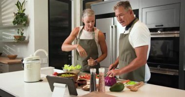 Olgun bir çift modern mutfakta birlikte sağlıklı salata hazırlıyor, yemek pişirmekten zevk alıyorlar. Mutfak, hazırlık, yerli, yaşam tarzı