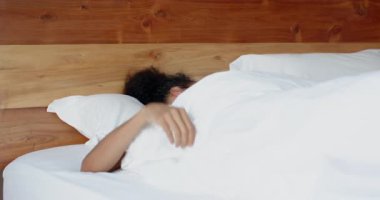 Kadın yatakta geriniyor, dinlenmiş ve güne hazır olarak uyanıyor, evde. Sabah, rahatlama, yaşam tarzı, sağlık, yatak odası, rutin