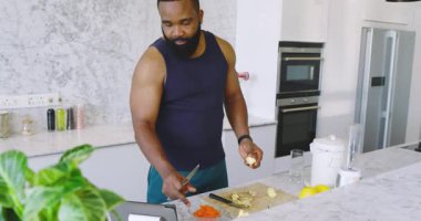 Afro-Amerikalı adam modern mutfakta yemek hazırlıyor. Bıçak, meyve, tablet, blender, lavabo. Yemek pişirme, yemek hazırlama, yaşam tarzı, sağlıklı, modern, parlak, mutfak.