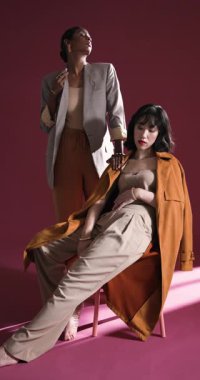 Dikey video: Stüdyoda modern moda sergileyen şık kıyafetler içindeki kendine güvenen kadınlar. stil, güven, giysi, giyim, güzellik, moda