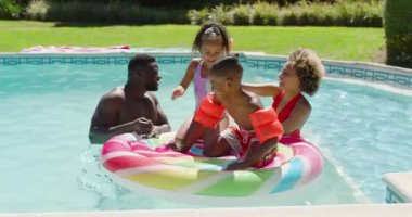 Çocuklar havuzda çırpınırken çocukları olan siyah bir baba yüzerek yüzüyor. Aile eğlencesi, havuz kenarında, canlı, eğlenceli, boş, neşeli, yaz mevsimi.