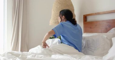 Pijamalı bir kadın evdeki rahat yatak odasında sabah kahvesinin tadını çıkarıyor. Rahatlama, sabah rutini, rahatlık, yaşam tarzı, sükunet, rahatlık