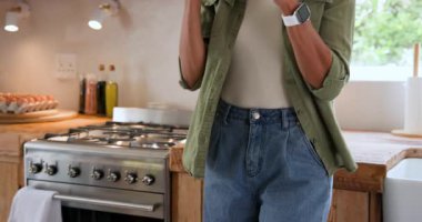 Modern mutfakta kahve içen, şık giyinen ve evde rahat giyinen bir kadın. Yaşam tarzı, sabah, teknoloji, moda, rahatlama, yerli