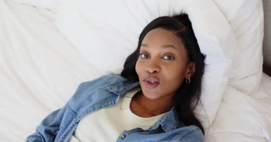 Şilte tıkırdatan, elinde kamera tutan Afro-Amerikan kadın yatak odasını çevirirken kendini tanıtıyor. Yaslanma, samimiyet, yaşam tarzı, minimalizm, samimi, doğal, gelişigüzel