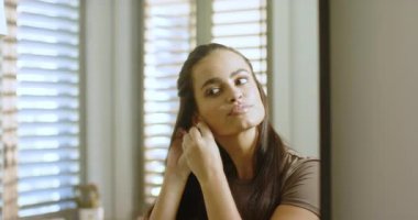 Smiling then looking into mirror at vanity, woman tucking hair, fastening earrings, getting ready. Mirror, grooming, elegance, fashion, beauty, selfcare, interior