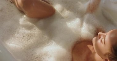 Kadın serbest küvette cam bardaktan köpük kaldırıyor ve rahatlamak için sıcak çay içiyor. Lüks, sükunet, spa, sükunet, minimalizm, refah, kişisel bakım