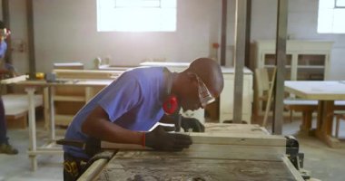 Afro-Amerikalı adam tezgah yerleştirme tezgahını testereyle kesiyor. Marangozluk, marangozluk, işçilik, sanayi, el işi, hassasiyet, atölye