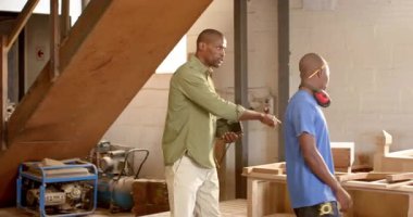 Afro-Amerikalı erkek iş arkadaşları tableti tıkırdatıyor, çerçeveyi seçiyor ve dükkanlara sığmak için eklemleri inceliyor. El işçiliği, takım çalışması, sanayi, atölye, akıl hocalığı, işbirliği, marangozluk