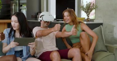 Farklı arkadaşlar oturma odasındaki kanepe tıkırtısı tabletine sanal yarış kulaklığı takarak tepki veriyorlar. Teknoloji, yenilik, işbirliği, eğlence, sürükleyici, yaşam tarzı, modern