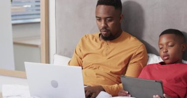 Afro-Amerikalı baba dizüstü bilgisayarda yazarken oğlunun yatakta yorganın altına hapsettiğini fark etmiş. Aile, bağlılık, şefkat, sıcaklık, rahatlama, samimiyet, samimiyet.