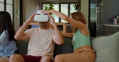 Çeşitli arkadaşlar VR kulaklıkları veriyor, tablet tıkırdatıyor ve koltukta oyun kontrollerini taklit ediyorlar. Etkileşimli, teknoloji, modern, eğlence, sosyal, sürükleyici, gündelik