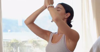 Genç bir kadın evde meditasyon yapıyor, gözleri kapalı, huzurlu ve rahat hissediyor. Sağlık, farkındalık, meditasyon, dinginlik, sükunet, rahatlama.