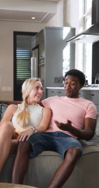 Dikey video: Genç bir çift evdeki kanepede dinleniyor, gülümsüyor ve birlikte vakit geçiriyorlar. Beraberlik, rahatlama, bağlanma, ilişki, mutluluk, rahatlık