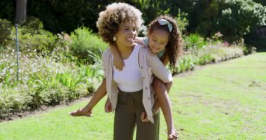 Çimenlerde oynayan, sırtında taşıdığı sırtında taşıdığı sırtından inen, gıdıklayan, ışıldayan çeşitli anne ve kızları var. Aile, bakım, açık hava, eğlence, mutluluk, şefkat, bağ