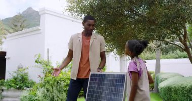 Bahçeye güneş paneli kuruluyor, Afrikalı Amerikalı baba ve çocuk yenilenebilir enerjiyi öğreniyor. eko-dost, sürdürülebilirlik, çevre, kurulum, eğitim, bağlanma