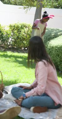 Dikey video: Aile güneşli bir günde piknik yapıyor, piknik sepetiyle çimlerin üzerinde oturuyor. Açık hava, rahatlama, rahatlama, doğa, yaz, kaynaşma