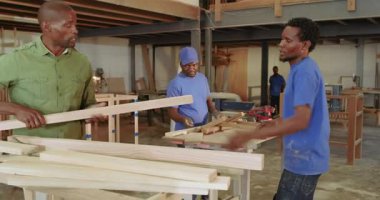 Atölyeye varan siyah erkek ustabaşı, asistan istifleme talimatı veriyor. El işi, takım çalışması, marangozluk, sanayi, el işi, organizasyon, eğitim